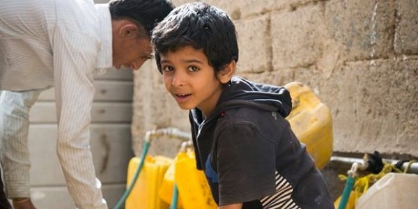 Young boy surrounded by yellow water buckets