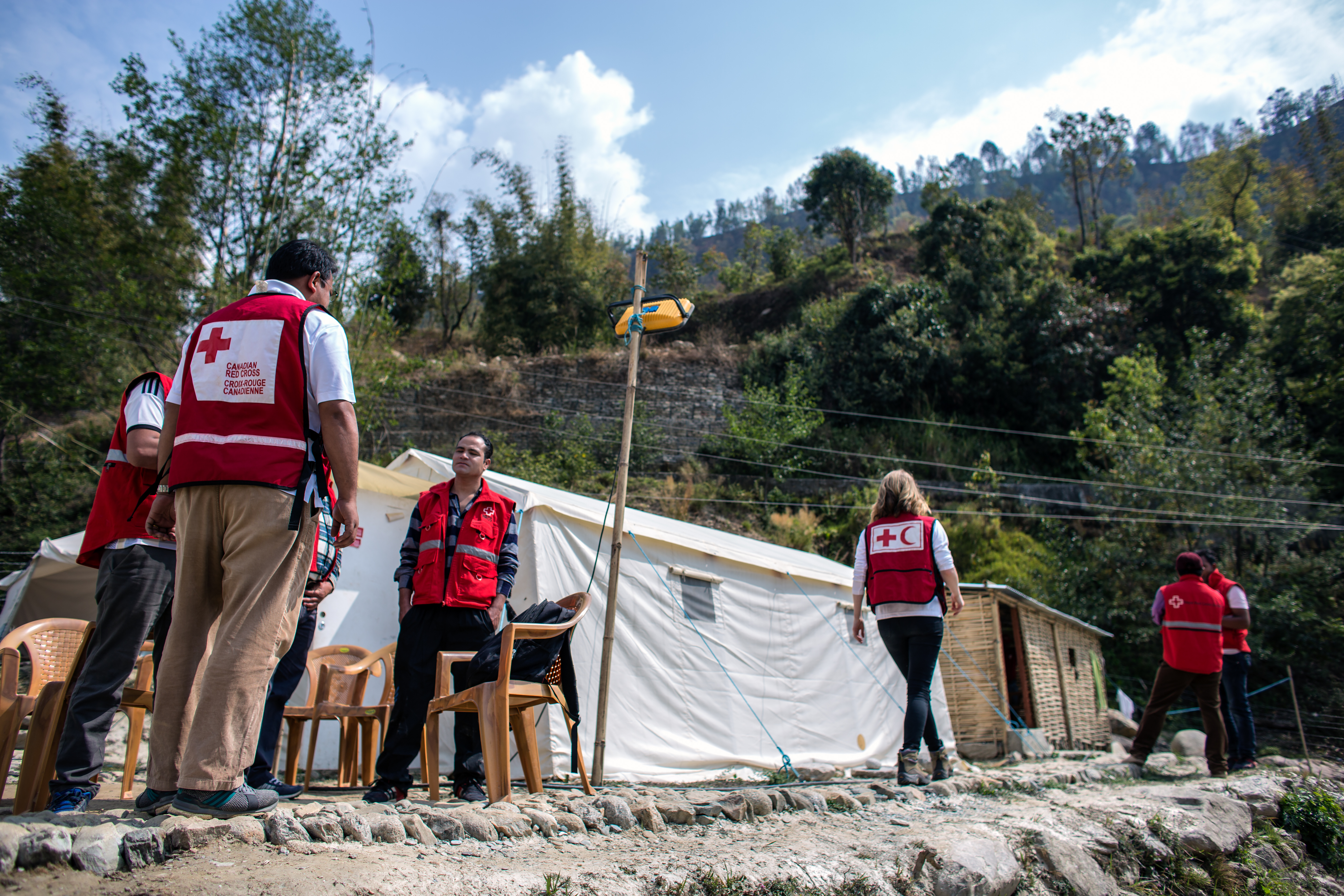 Des personnes vêtues de vestes rouges se rassemblent autour de tentes.