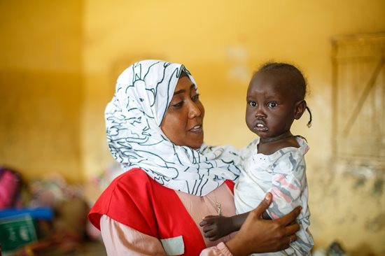 Wajdan Hassan Ahmed, infirmière bénévole du Croissant-Rouge soudanais, tient une fillette dans ses bras