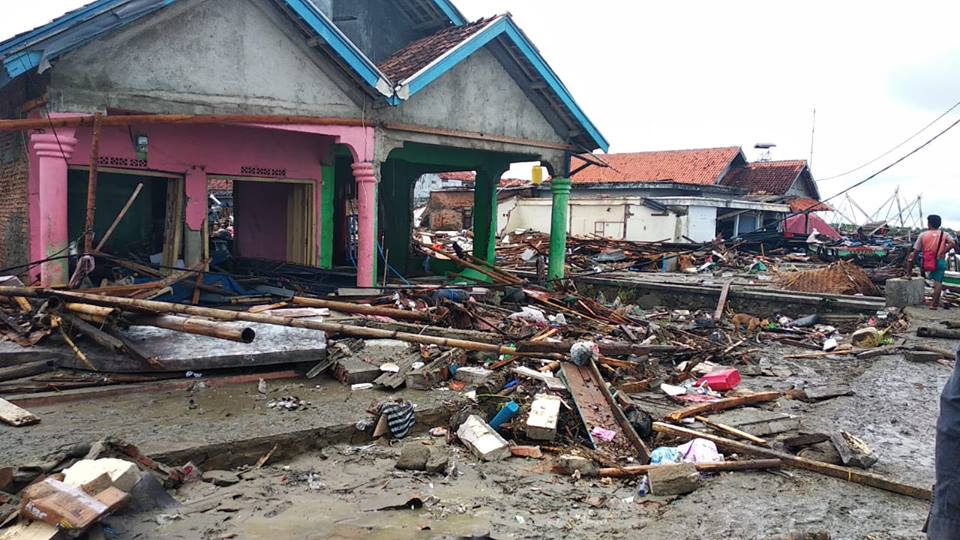 Une maison endommagée par un tsunami est entourée de débris.