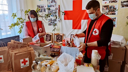 Deux membres du personnel de la Croix-Rouge emballant des objets dans des boîtes.