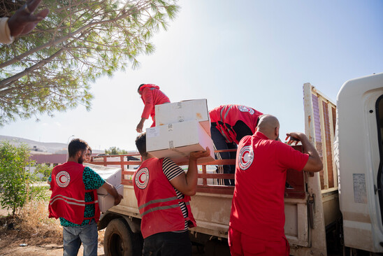 Un groupe de personnes portant des dossards du Croissant-Rouge déchargent un camion.